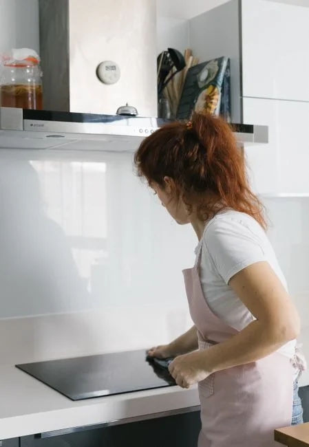 A professional cleaner wearing protective gear is vacuuming the floor in a contemporary living room.